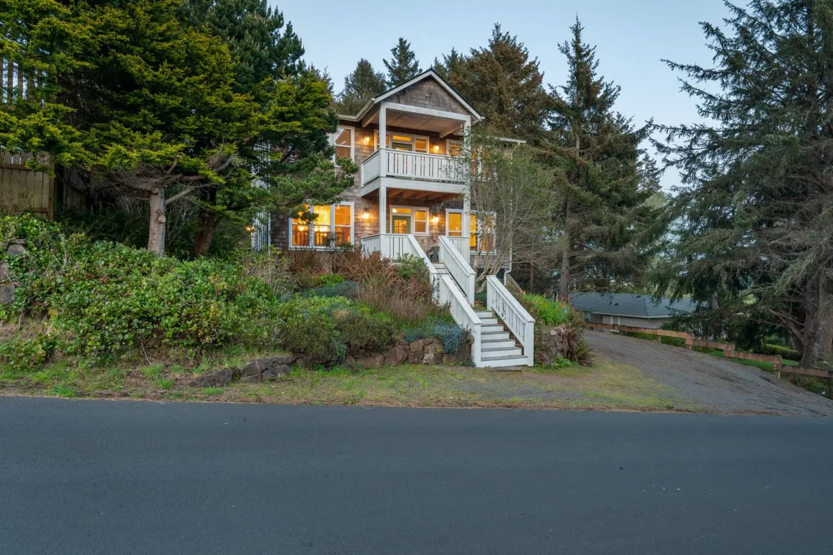 The exterior of Pacific Star, featuring a welcoming front porch, large windows that hint at the open-concept interiors, and a landscaped garden. The porch is perfect for relaxing or gathering with family and friends, while the lush greenery connects the home to its natural surroundings.
