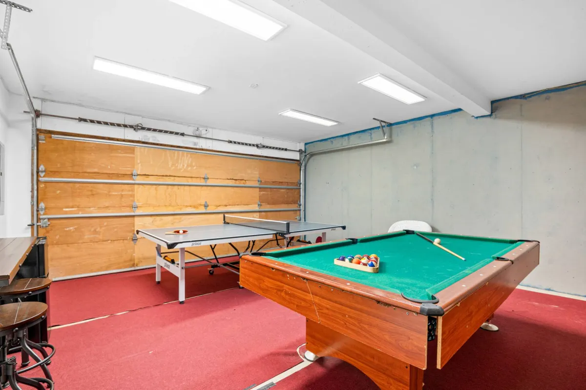 A vibrant recreational space featuring both a pool table and a ping pong table, with bar stools nearby. The room is bright and spacious, embodying a playful and relaxed mood ideal for friendly competitions and group activities.