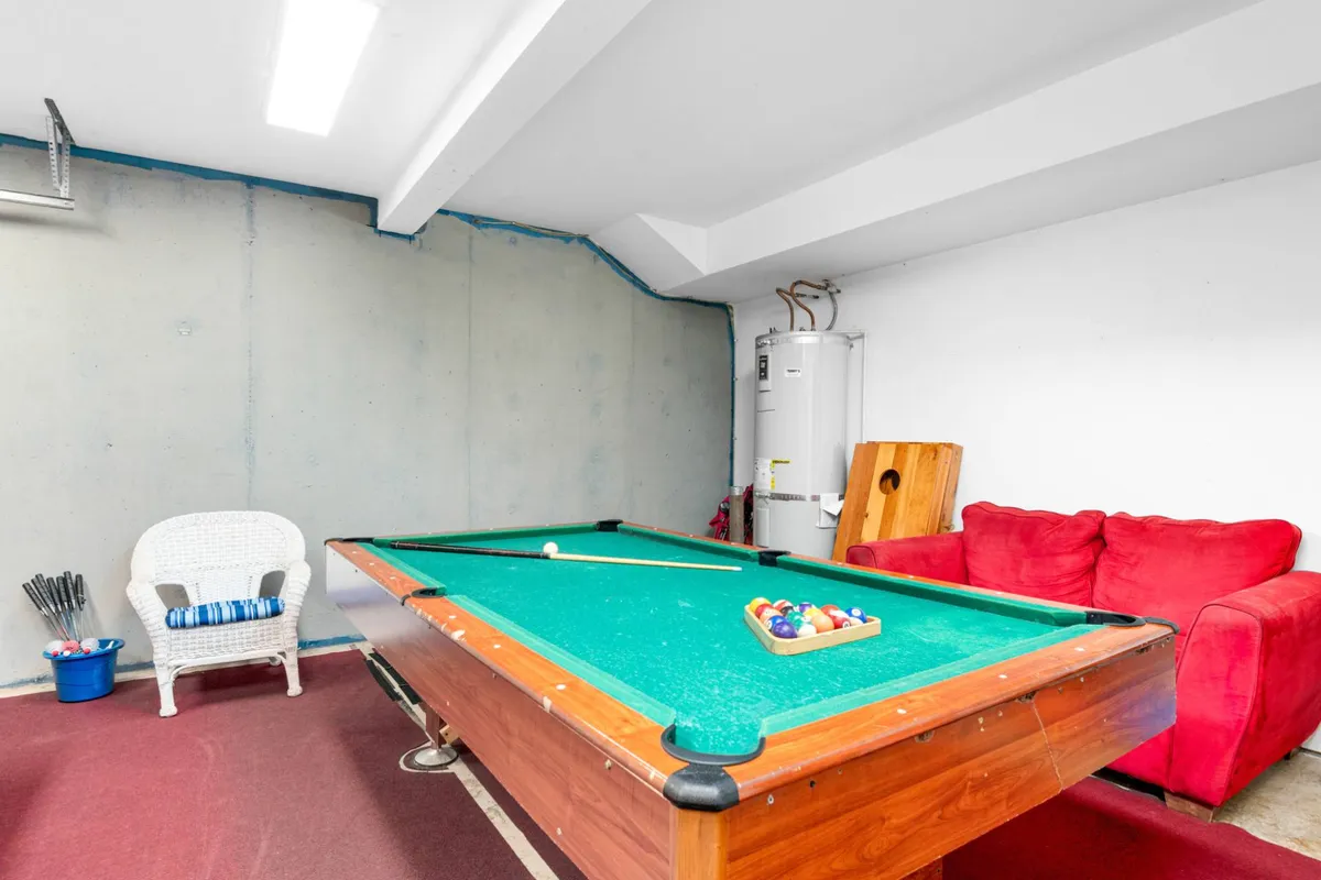 A playful and relaxed indoor setting featuring a pool table, red couch, and white chair—ideal for friendly competitions and memorable gatherings as described in the section. The space is casual and invites group activities.