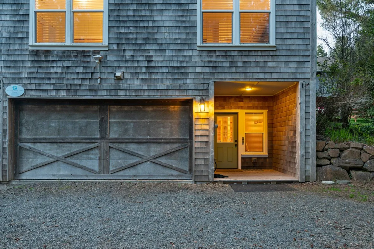 This exterior shot shows the warmly lit entrance and garage door of the home, hinting at the converted garage game room described in the section. The inviting glow suggests an atmosphere ready for activity regardless of the weather and highlights the welcoming aspect of the property.