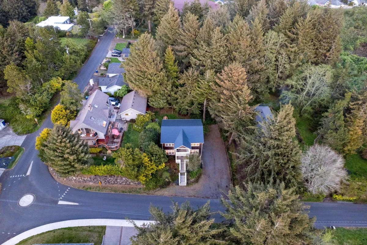 A wide exterior view of the main house set among trees, featuring spacious outdoor areas suitable for family gatherings, games, and barbecues. The tranquil setting aligns with outdoor activities like horseshoes, picnics, and play for kids.