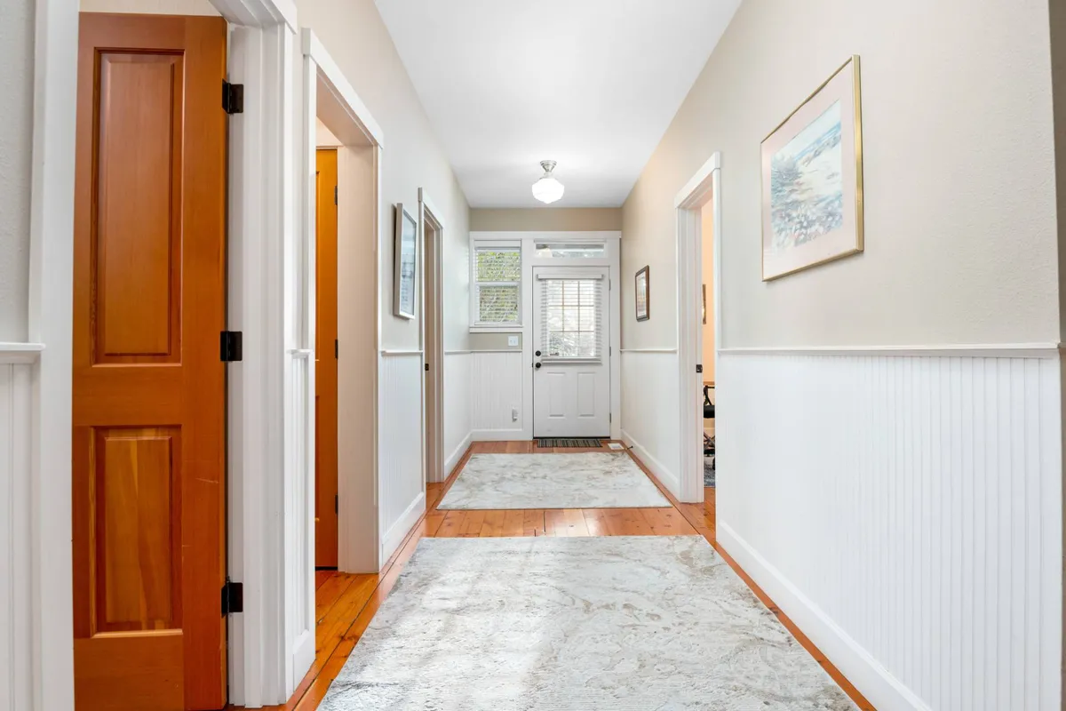 A bright, welcoming entryway featuring wooden doors, a hallway rug, and a stylish light fixture. The entrance exudes warmth and sets the stage for the home's inviting atmosphere.